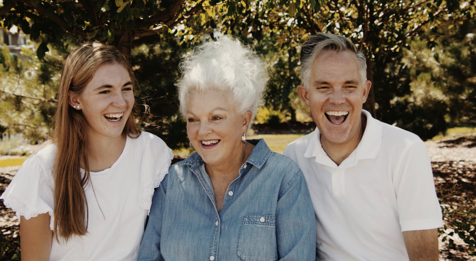 Three generations laughing together — daughter, grandmother, and son