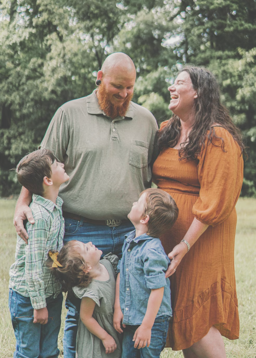 Young family with three kids laughing in a field