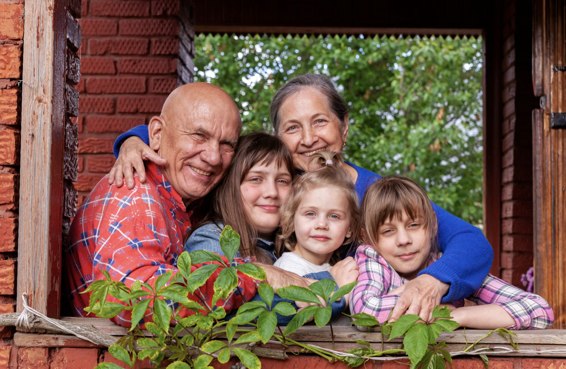 Grandparents and grandchildren hugging at a window